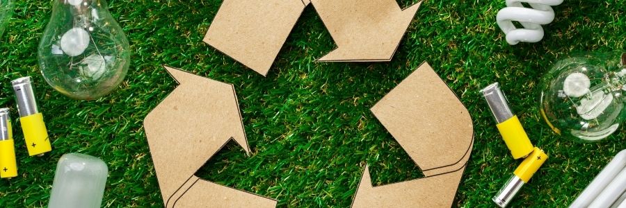 lightbulbs batteries on grass with recycle sign